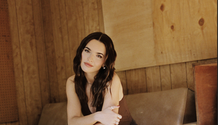 A woman with brunette hair is sitting on a couch, and her arms crossed.